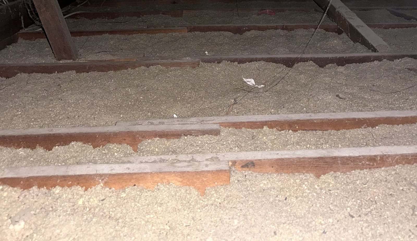 Attic floor with loose-fill insulation between the joists and loose debris lying on top